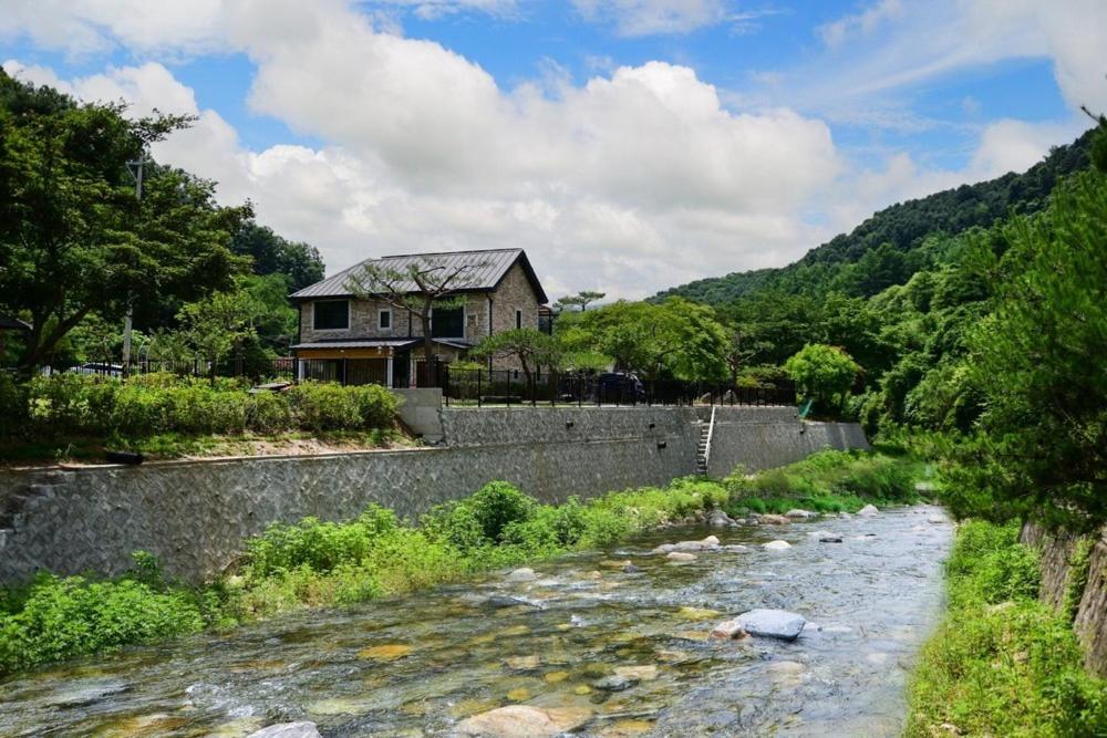 a house on a retaining wall next to a river at Gapyeong La Vie En Rose Private Pension in Gapyeong