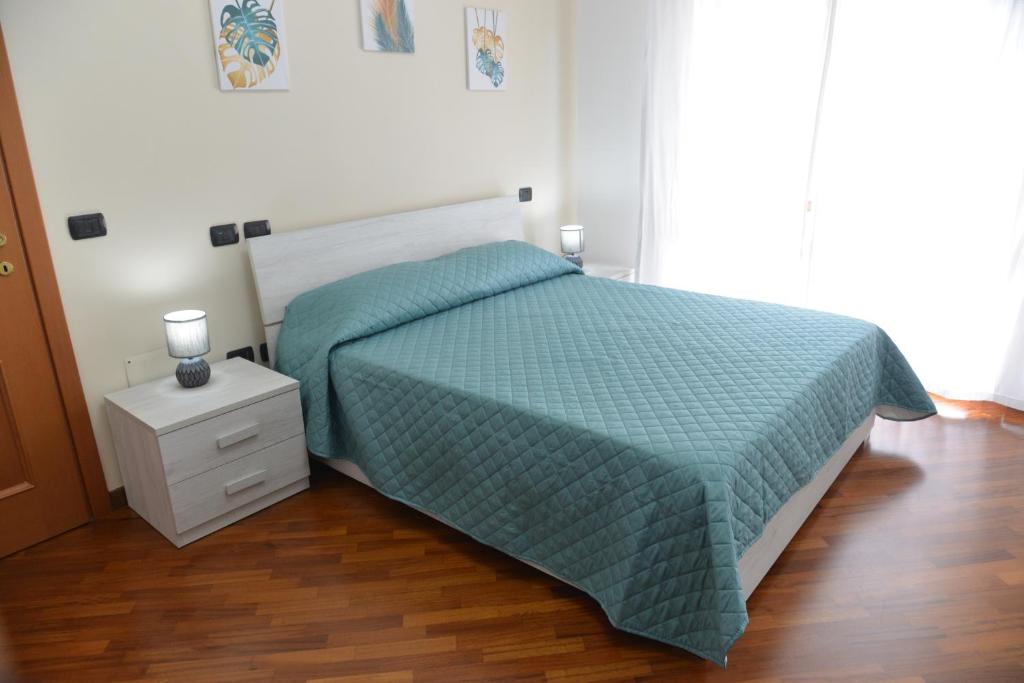 a bedroom with a bed with a green comforter at Luciana Apt - 3 min train to FCO Airport & Fiera in Fiumicino