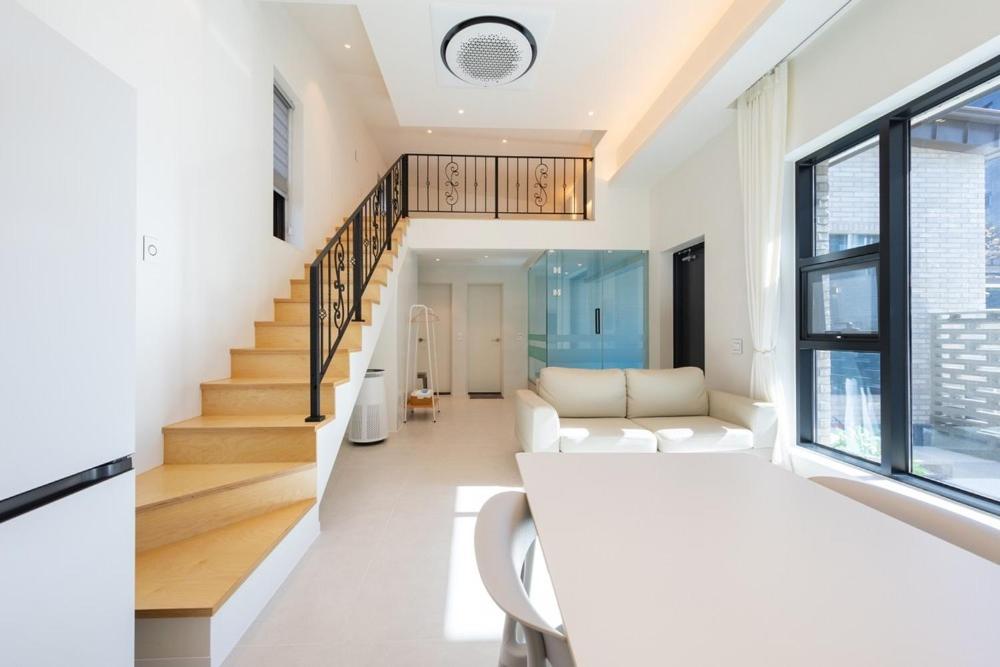 a living room with white furniture and a staircase at Gangneung Gyeongpo 345 Pool Villa in Kyŏngp'o-mal