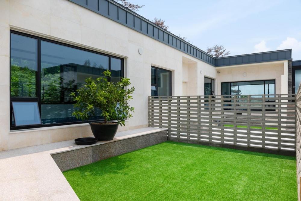 une maison avec une pelouse verte devant dans l'établissement Gangneung Ranteuruhe Pension, à Gangneung