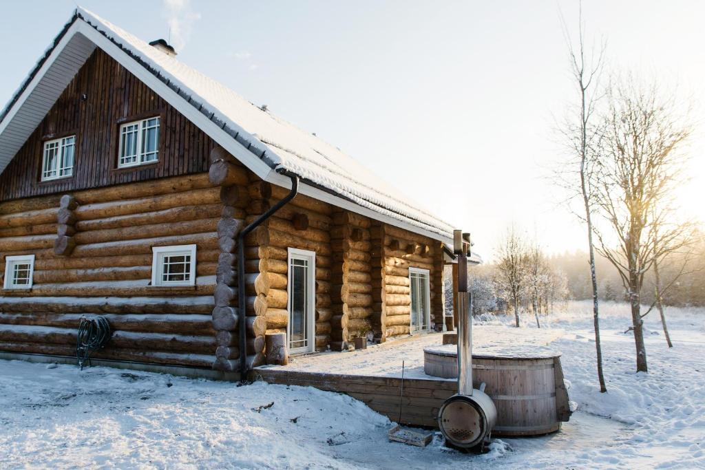 a log cabin in the snow with a tub at Humala Holiday Home in Kohila