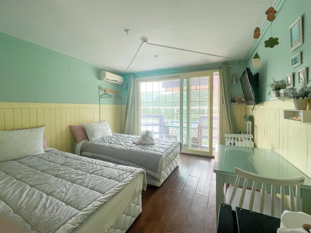 a bedroom with two beds and a desk and a window at Riverwalk Pension Chuncheon in Paegyang