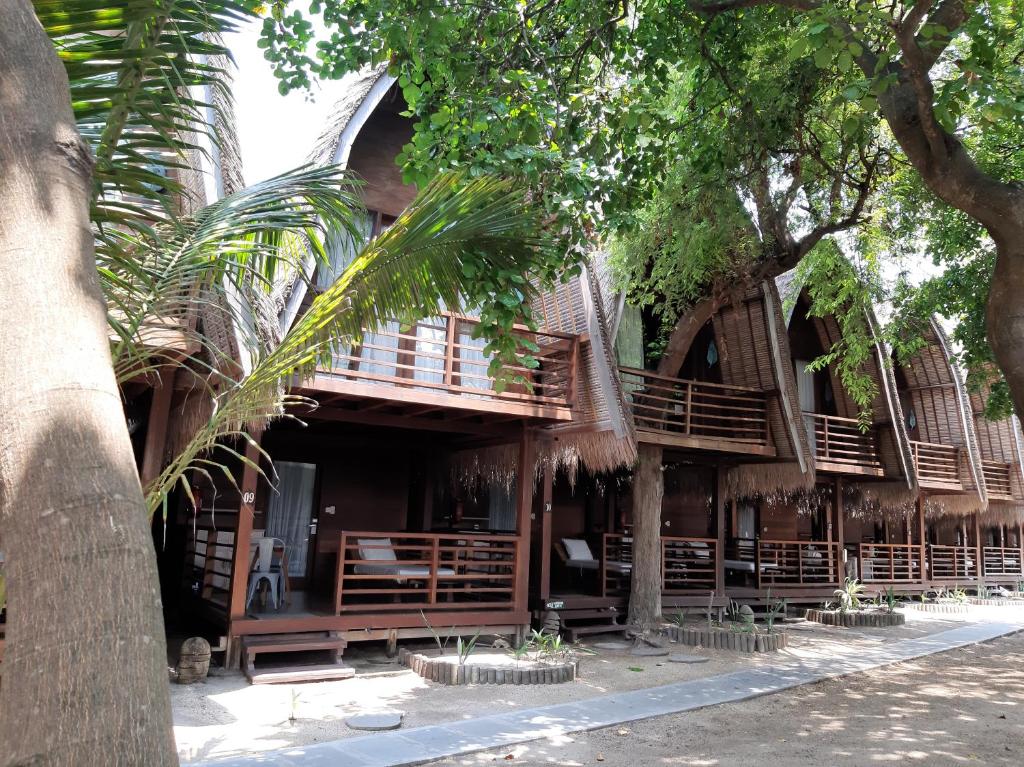 a building with wooden balconies and trees at Mola2 Resort Gili Air in Gili Islands