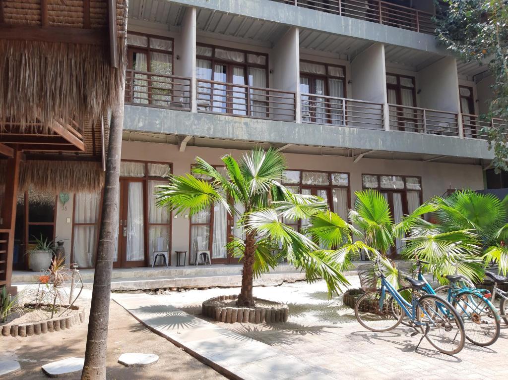 two bikes parked in front of a building with palm trees at Mola2 Resort Gili Air in Gili Islands