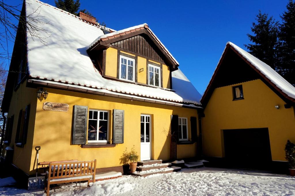 a yellow house with a bench in front of it at Pokoje Gościnne Parkowa 2 in Świeradów-Zdrój