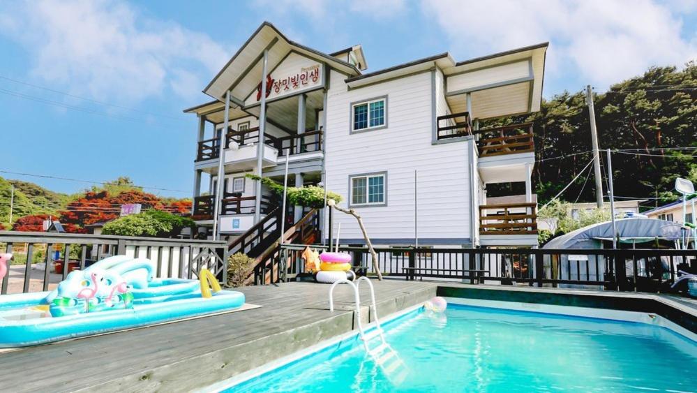 a resort with a swimming pool and a building at Rose Life Stay Pension in Taean