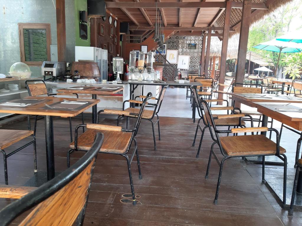 a restaurant with wooden tables and chairs in a room at Mola2 Resort Gili Air in Gili Islands