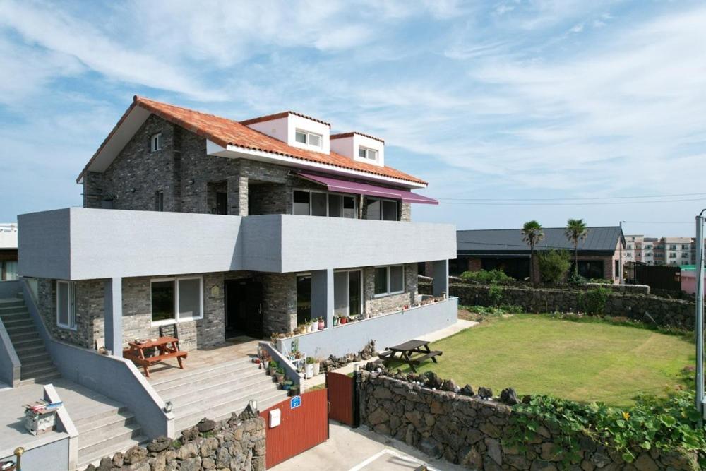Una casa grande con un gran patio delante de ella. en Yeonmi Dongsan, en Jeju