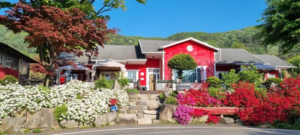 a red house with flowers in front of it at Hoengseong Olympus Pension in Hoengseong