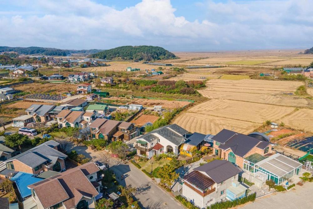 an aerial view of a village with a field and houses at Daebudo Siesta Pension in Ansan