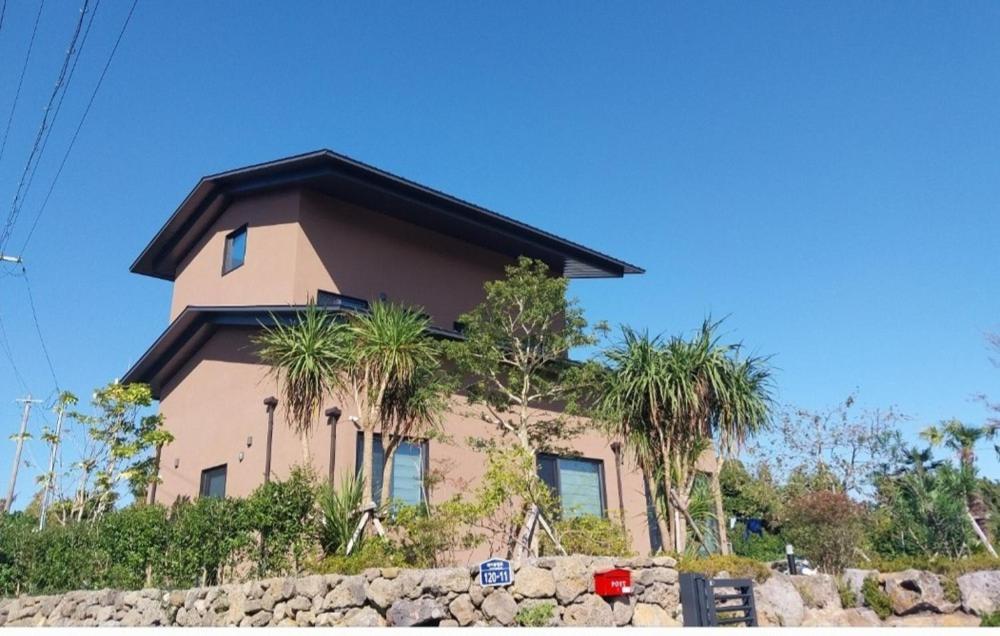 a house with palm trees in front of it at Seogwipo Wimiga Yeon in Seogwipo