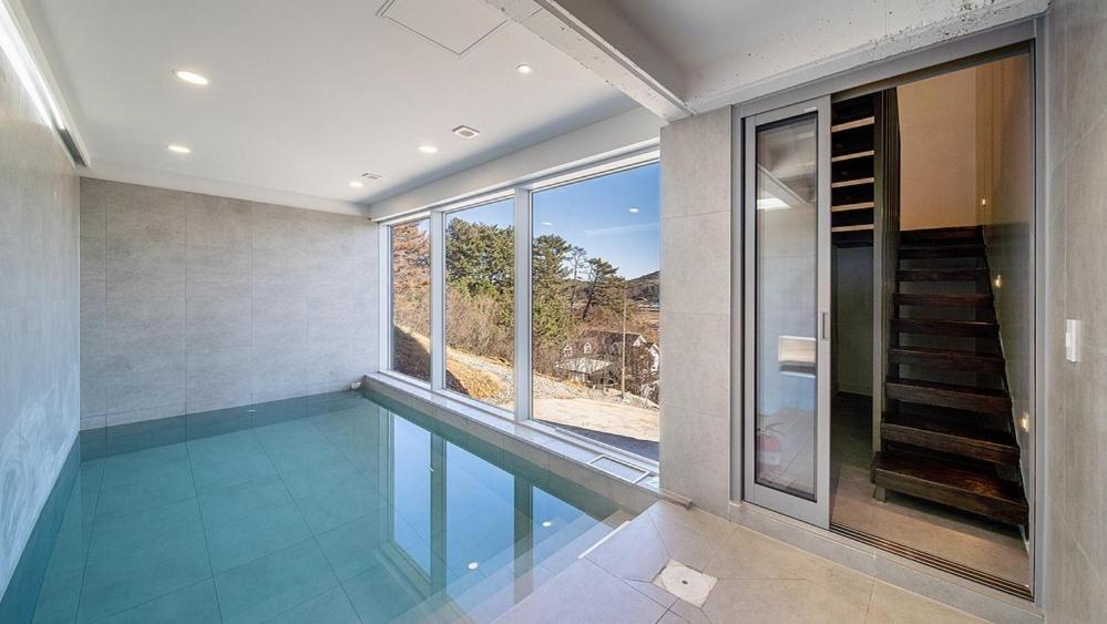 an empty swimming pool in a house with a window at Taean Oaten Pool Villa in Taean