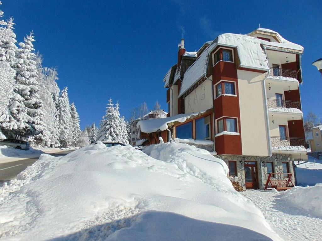 budynek pokryty śniegiem obok stosu śniegu w obiekcie Vila Trag w mieście Kopaonik