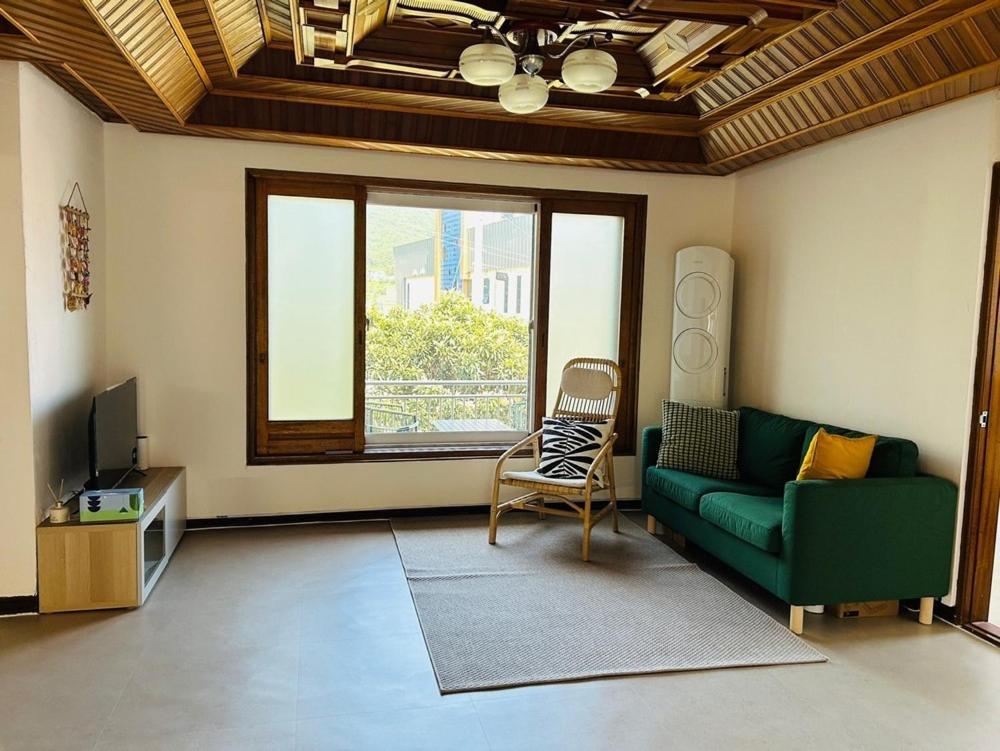 ナムヘにあるNamhae Western Houseのリビングルーム(緑のソファ、窓付)