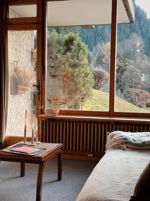 - une chambre avec une grande fenêtre, une table et un lit dans l'établissement Blanches Alpes Appartement Megève, à Megève