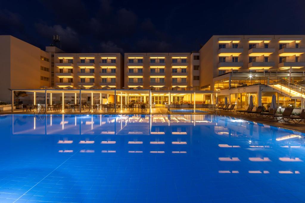 a large pool in front of a hotel at night at Queens Bay Hotel in Paphos