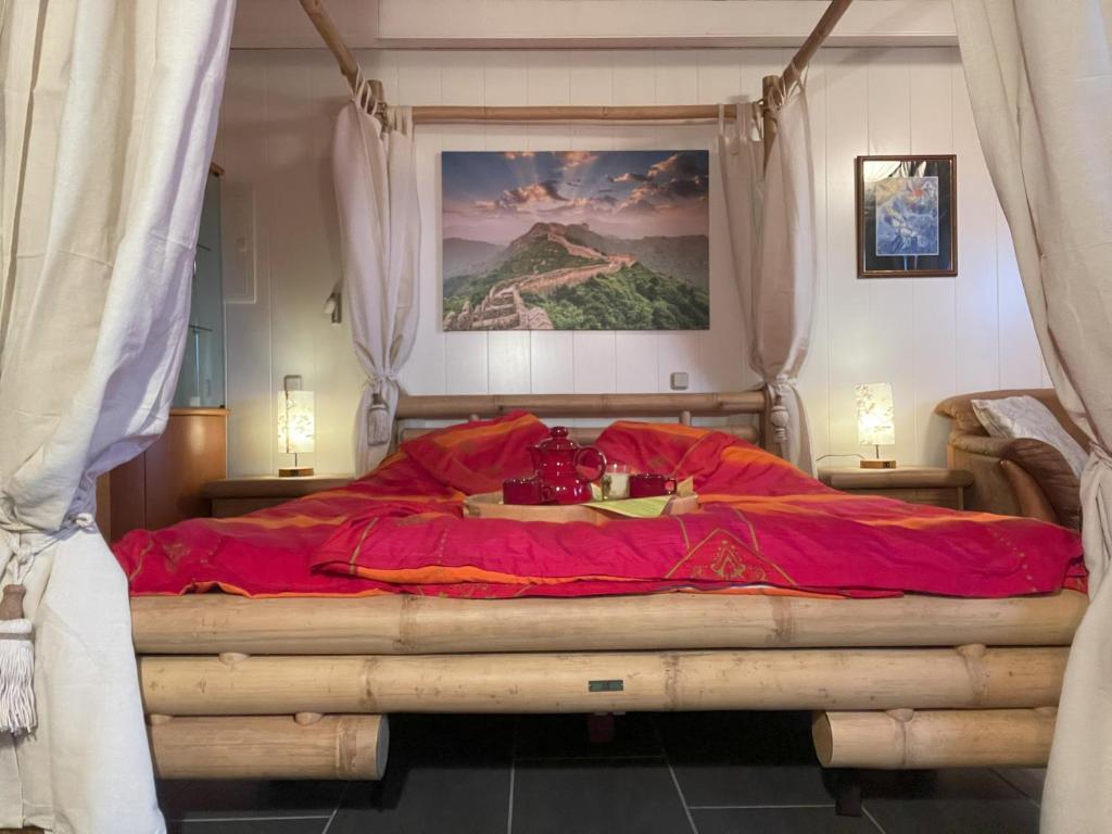a bedroom with a large bed with red sheets at Berghof Arnika in Sankt Andreasberg