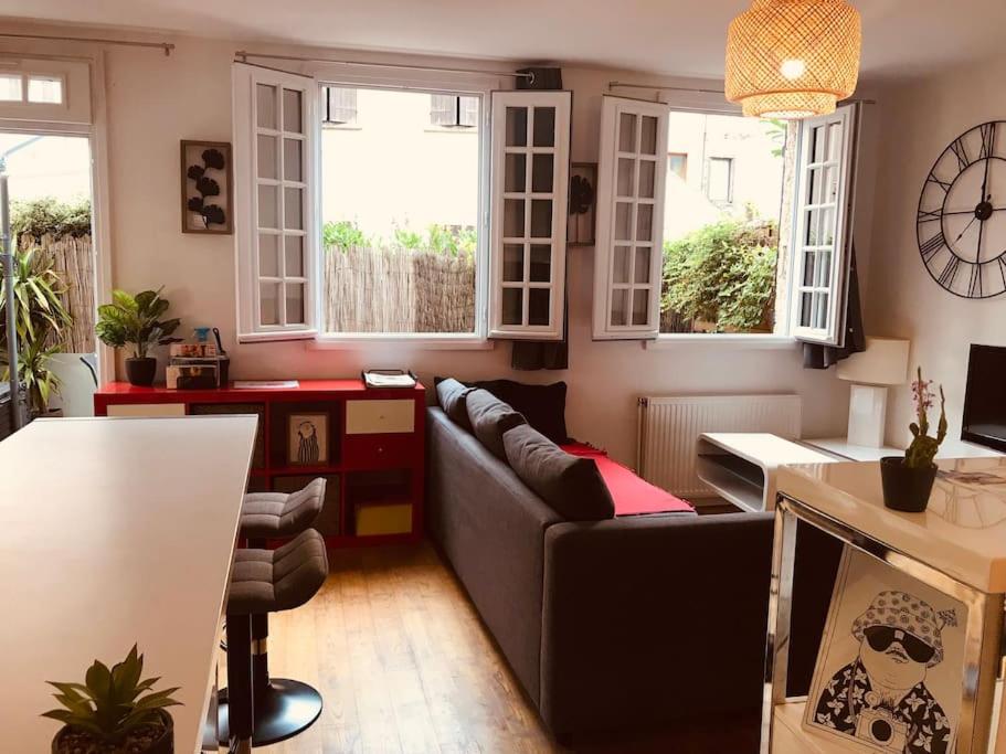 un salon avec un canapé et quelques fenêtres dans l'établissement Appart Terrasse Centre ville Parking facile, à Auxerre