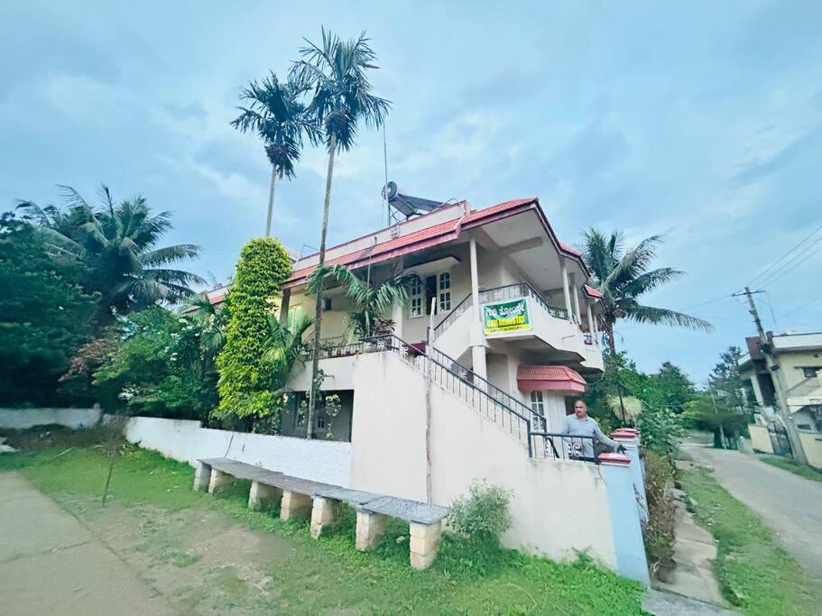 a man sitting on a porch of a house at GURI Homestay in Kushālnagar
