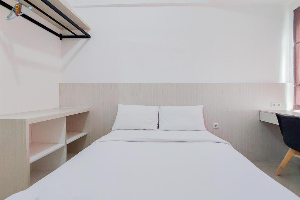 a white bed in a room with a desk and a bed sidx sidx at Minimalist Studio at Poris 88 Apartment By Travelio in Tangerang