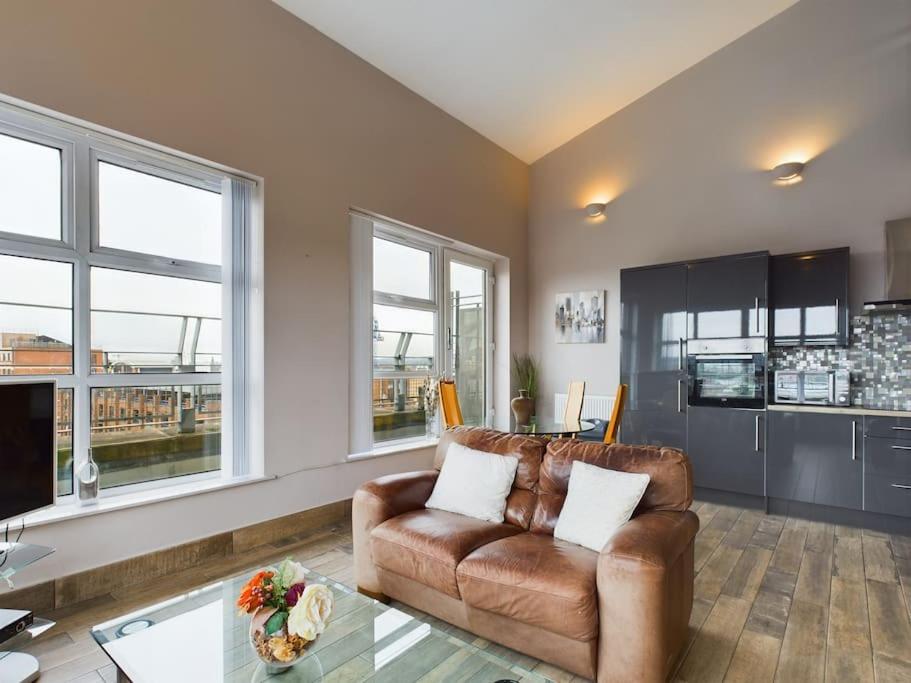 a living room with a leather couch and a table at Stunning 2BR Apt in City Centre in Belfast