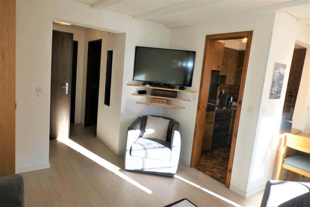 a living room with a television and a chair at Chalet Valeria in Saas-Fee