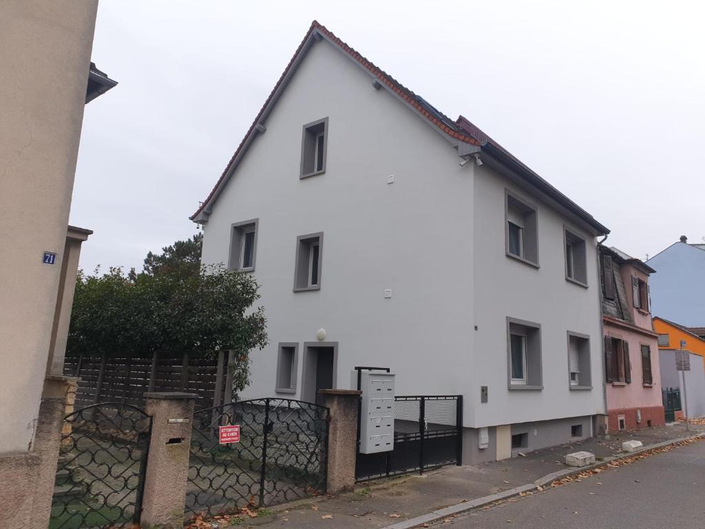 une maison blanche avec une clôture devant dans l'établissement Authentique Appartement cosy, à Schiltigheim