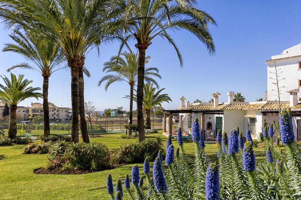 a garden with palm trees and blue flowers at F04 Bahia Playa - Apartment in Mijas Costa