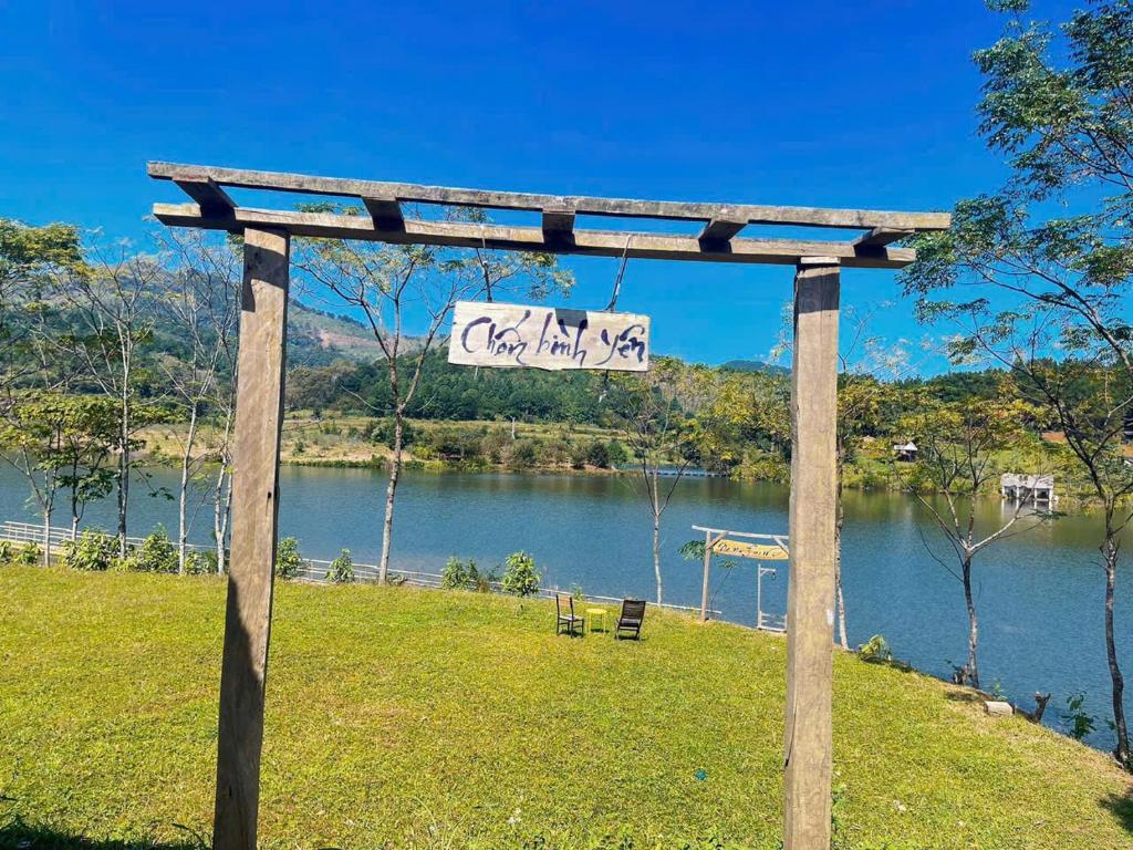 Una pérgola de madera con un cartel frente a un lago. en NaNa Farm, en Bak Kan