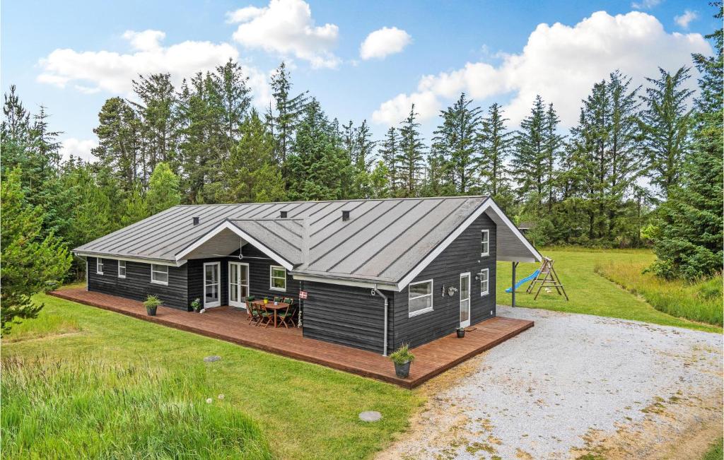 a black cabin with a deck and a playground at Casa Fortuna in Bindslev
