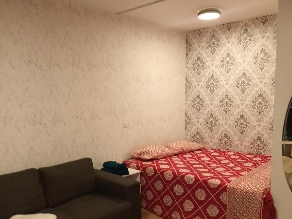 une petite chambre avec un lit et un canapé dans l'établissement Apartment near tikkurila railwaystation with free parking, à Vantaa