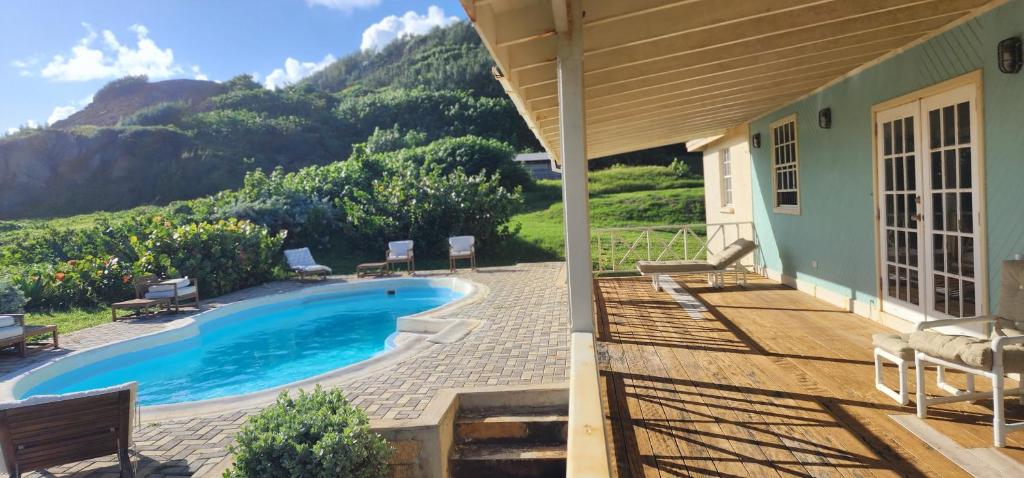 a house with a swimming pool with mountains in the background at Santosha Barbados in Saint Andrew