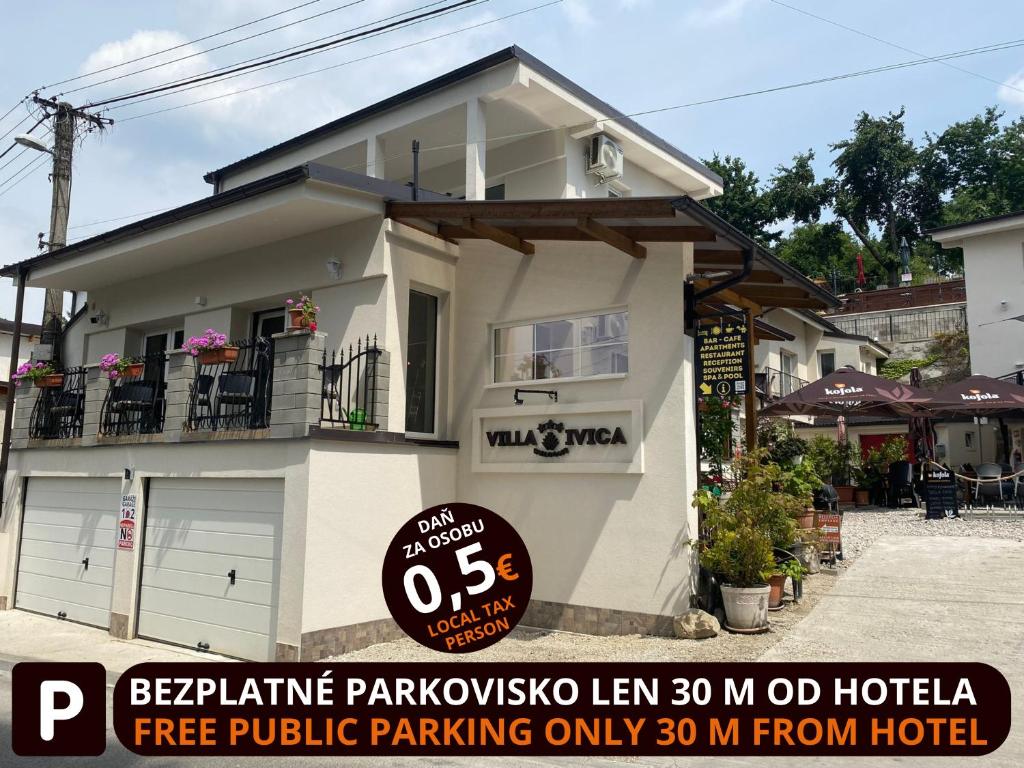 a white house with a sign in front of it at Spa & Pool Apartments Prestige VILLA IVICA in Bratislava