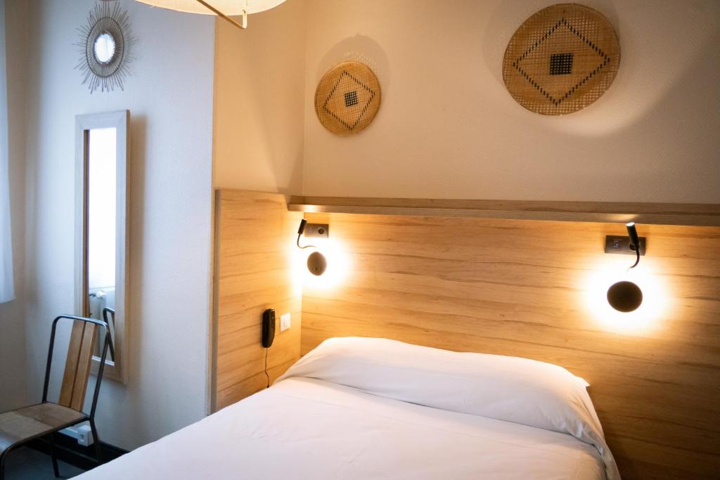 a bedroom with a white bed with a wooden headboard at Hôtel de la gare in Choisy-le-Roi