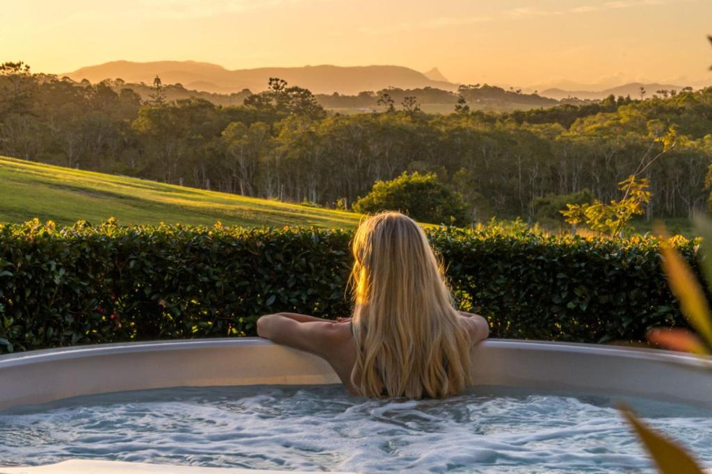 a woman sitting in a hot tub watching the sunset at Cape Byron Suite 5 Private Suite with Ensuite in Byron Bay