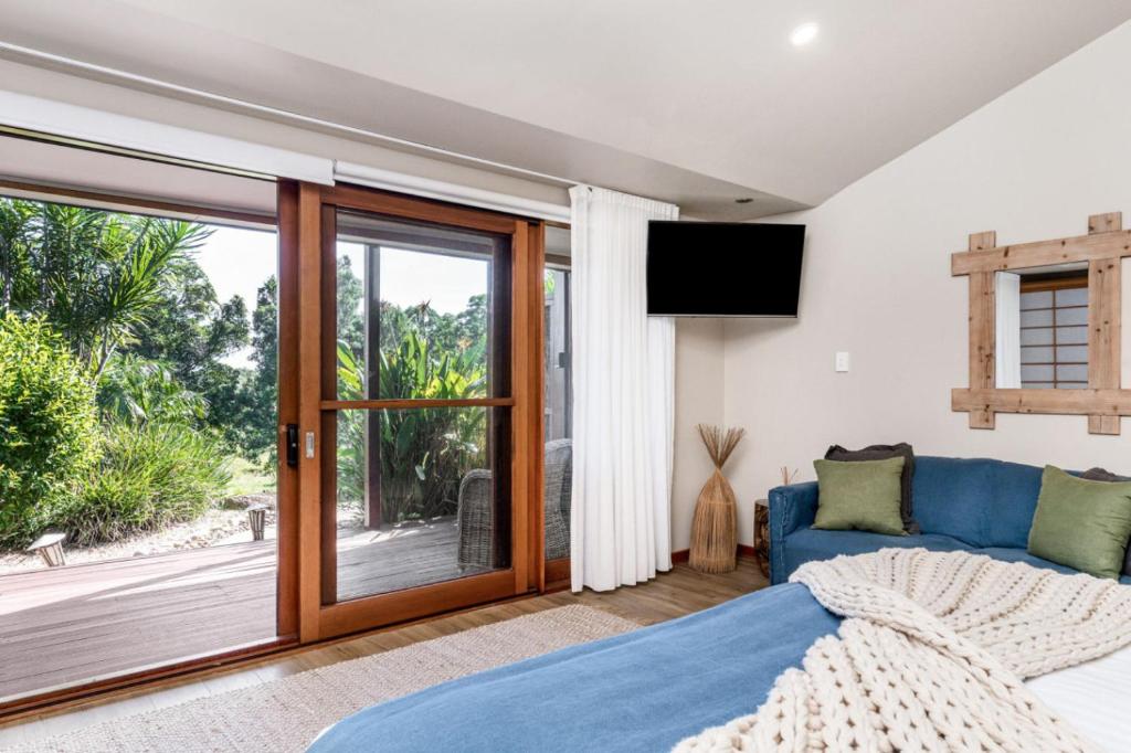 a bedroom with a blue bed and a sliding glass door at Cape Byron Suite 5 Private Suite with Ensuite in Byron Bay