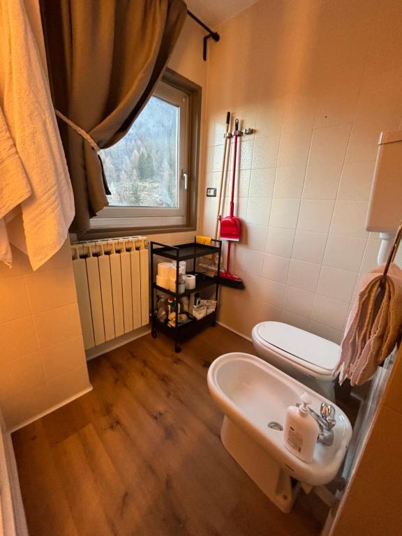 łazienka z umywalką, toaletą i oknem w obiekcie Casa Porrone w mieście Passo del Tonale