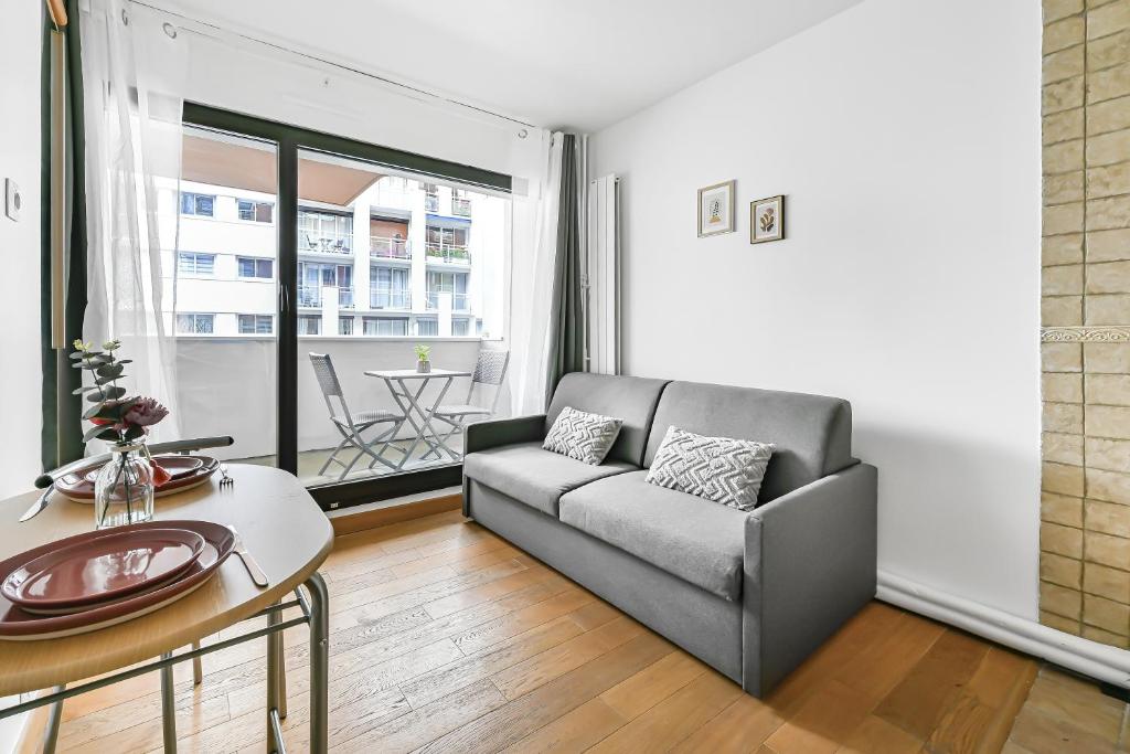 un salon avec un canapé et une table dans l'établissement La Felicita - Studio avec Balcon Paris - Netflix, à Paris