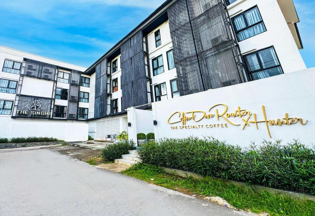 an apartment building with a sign in front of it at Collection O The Singha Chiangmai Hotel in Chiang Mai