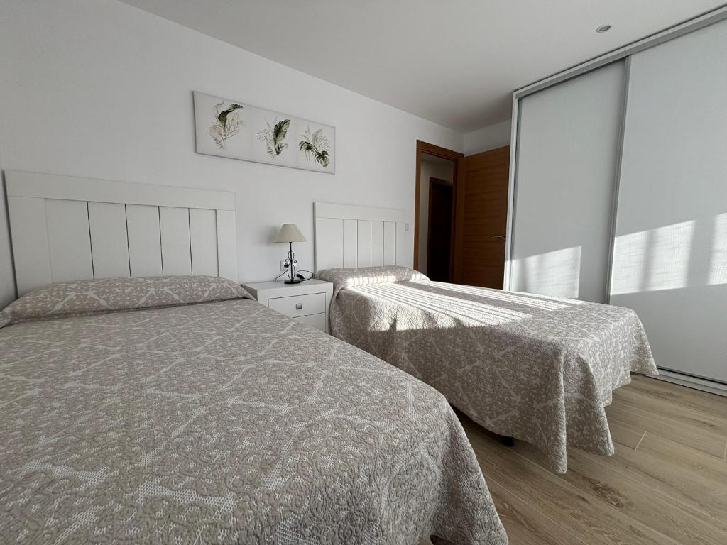 ein Schlafzimmer mit zwei Betten und einem großen Fenster in der Unterkunft Piso en Ribeira a 20metros de la playa de Coroso by Cristian&Tamara "alquileres" in Ribeira