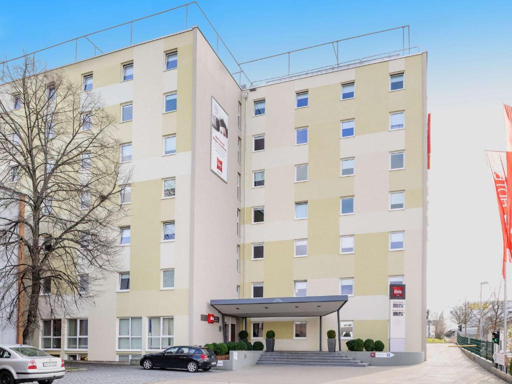 a large white building with a car parked in front at ibis Stuttgart Airport Messe in Leinfelden-Echterdingen