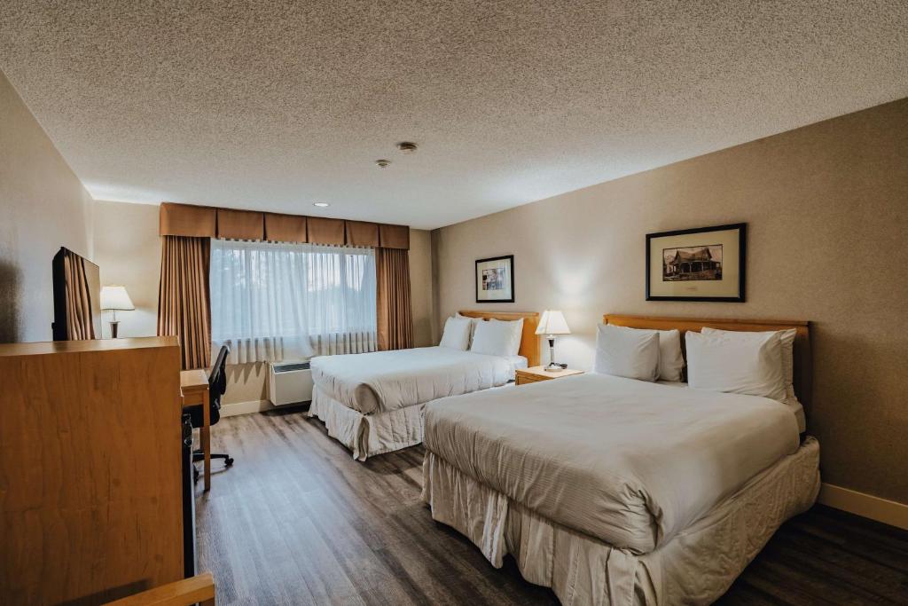 a hotel room with two beds and a desk at SureStay Plus by Best Western Coquitlam in Coquitlam