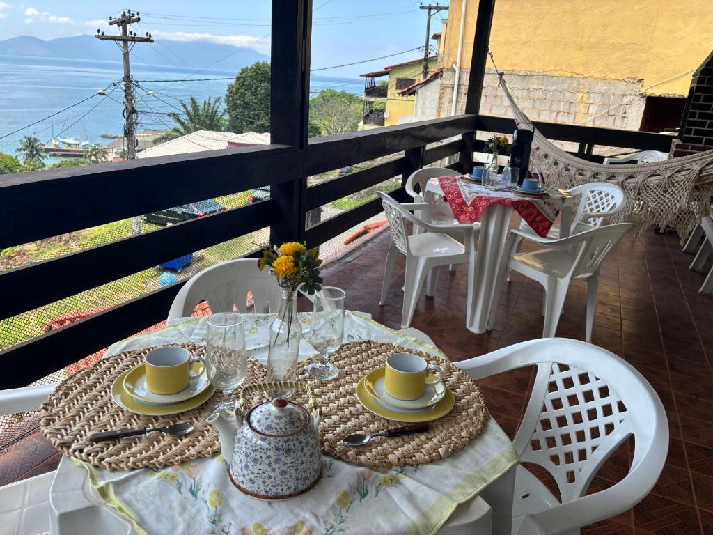 a table with cups and saucers on a balcony at Casa ampla com vista para o mar in Mangaratiba