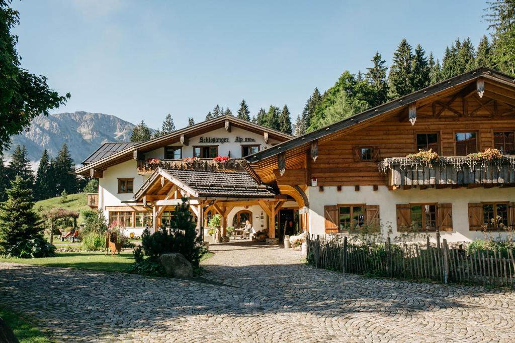 a large wooden house in the mountains with a yard at Berghotel Schlossanger Alp in Pfronten