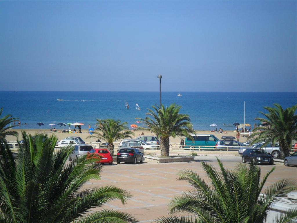 um parque de estacionamento na praia com palmeiras e o oceano em Appartamenti Bramante em Vieste