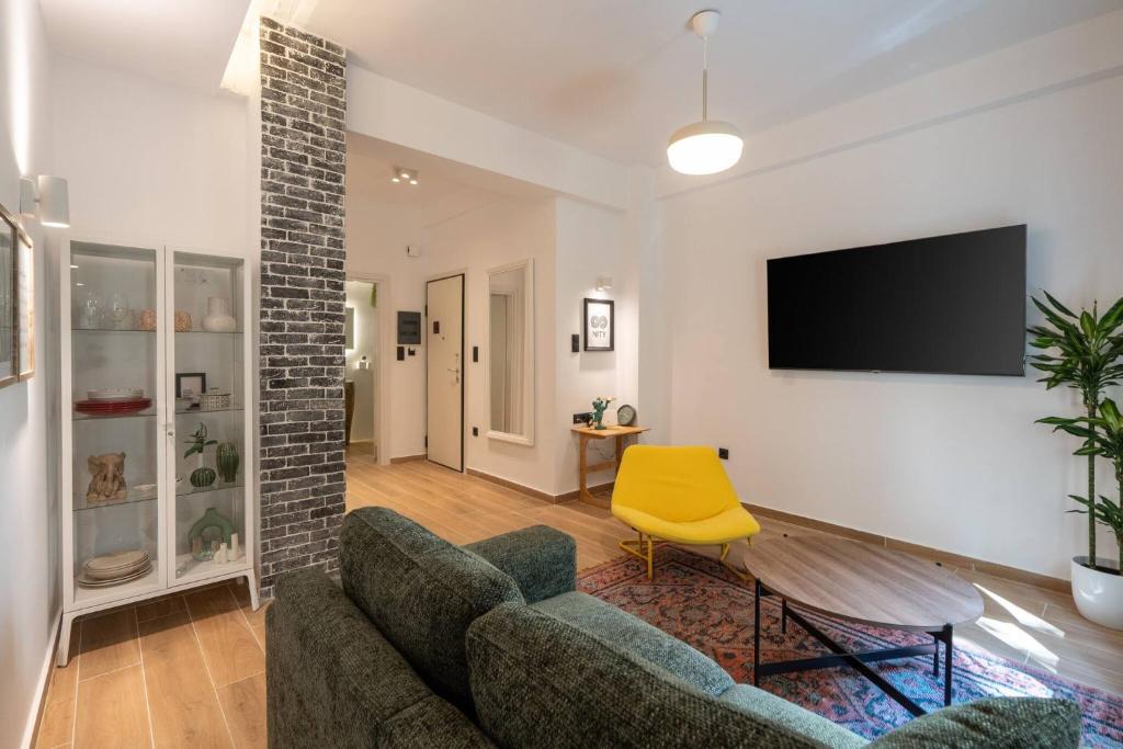 a living room with a couch and a tv on a wall at 1BR Stylish Apt 20 Minutes from Acropolis in Athens