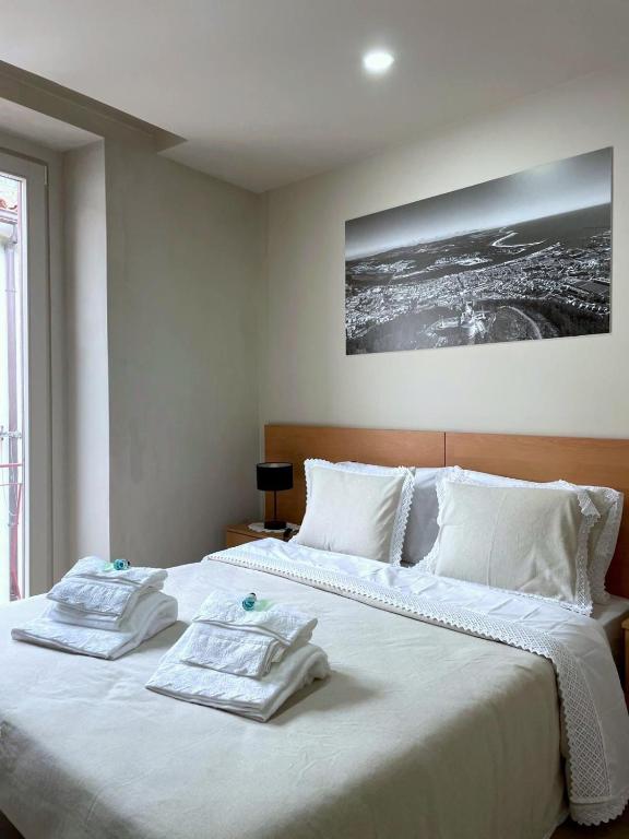 a bedroom with a large white bed with two towels on it at CasAmalia 54 in Viana do Castelo