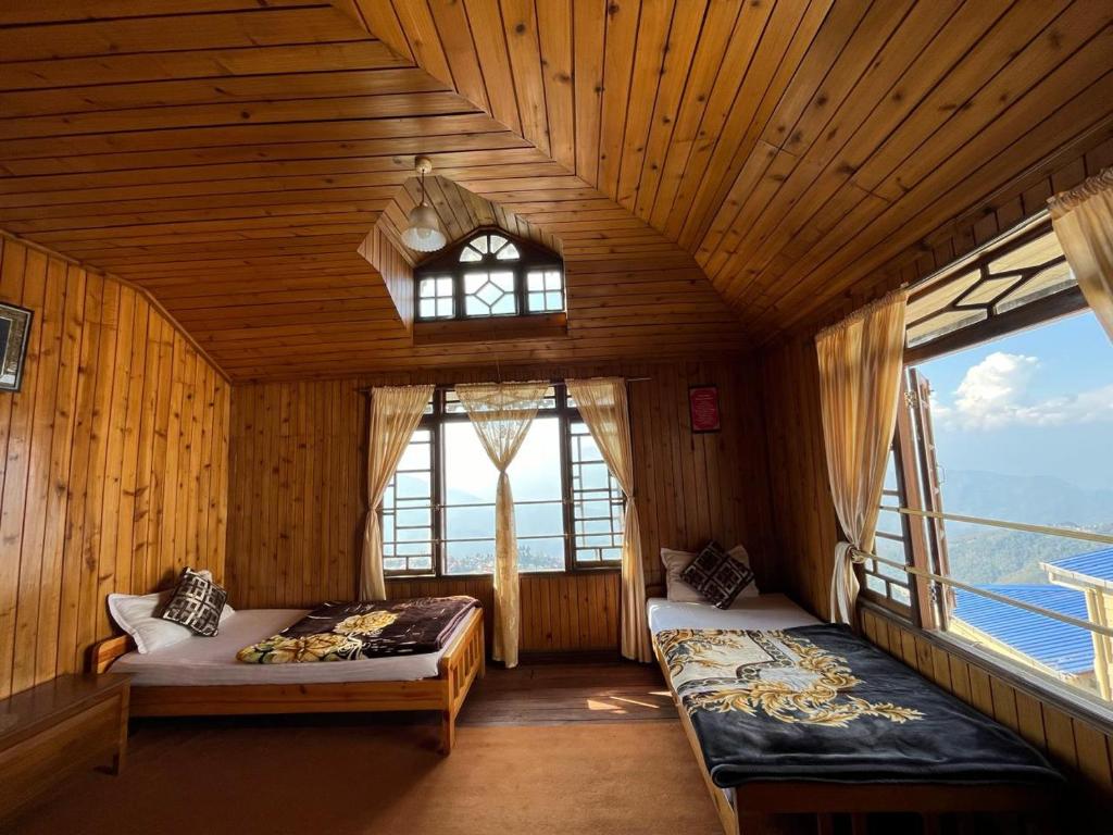Un dormitorio con dos camas en una habitación con ventanas. en Eagle's Nest Homestay, en Darjeeling