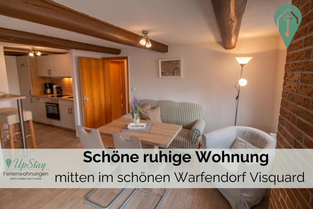 a living room with a table and a kitchen at Butzenhuuske in Krummhörn