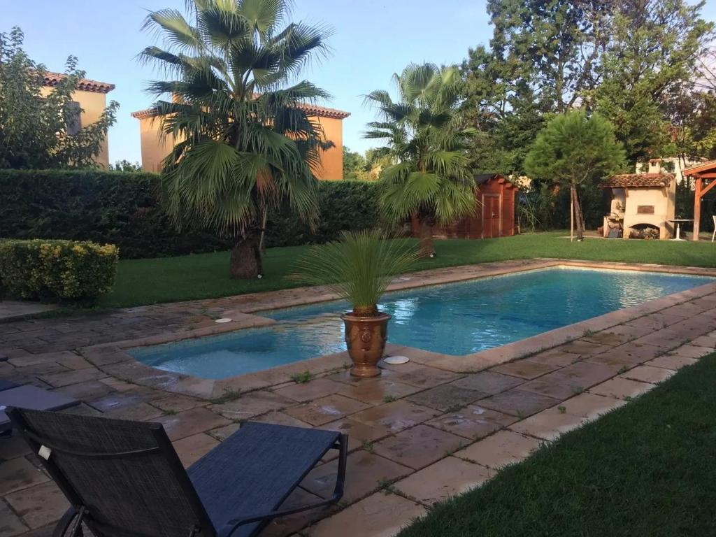 - une piscine dans une cour avec 2 chaises et un palmier dans l'établissement Appartement confortable à Plan-de-Cuques avec piscine privée, à Plan-de-Cuques